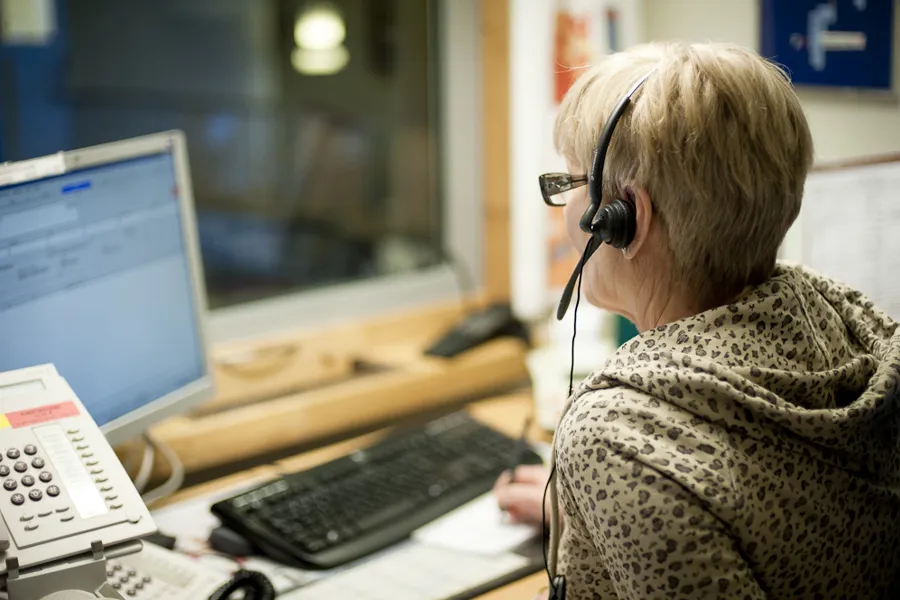 En person som har på seg et headset og sitter ved en datamaskin