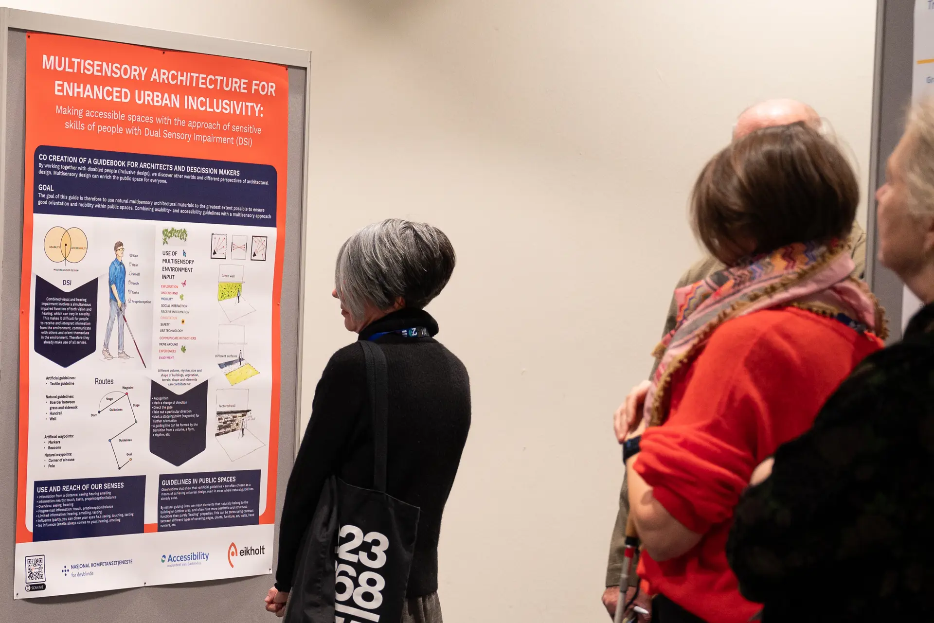 En gruppe mennesker som ser på en plakat på en vegg