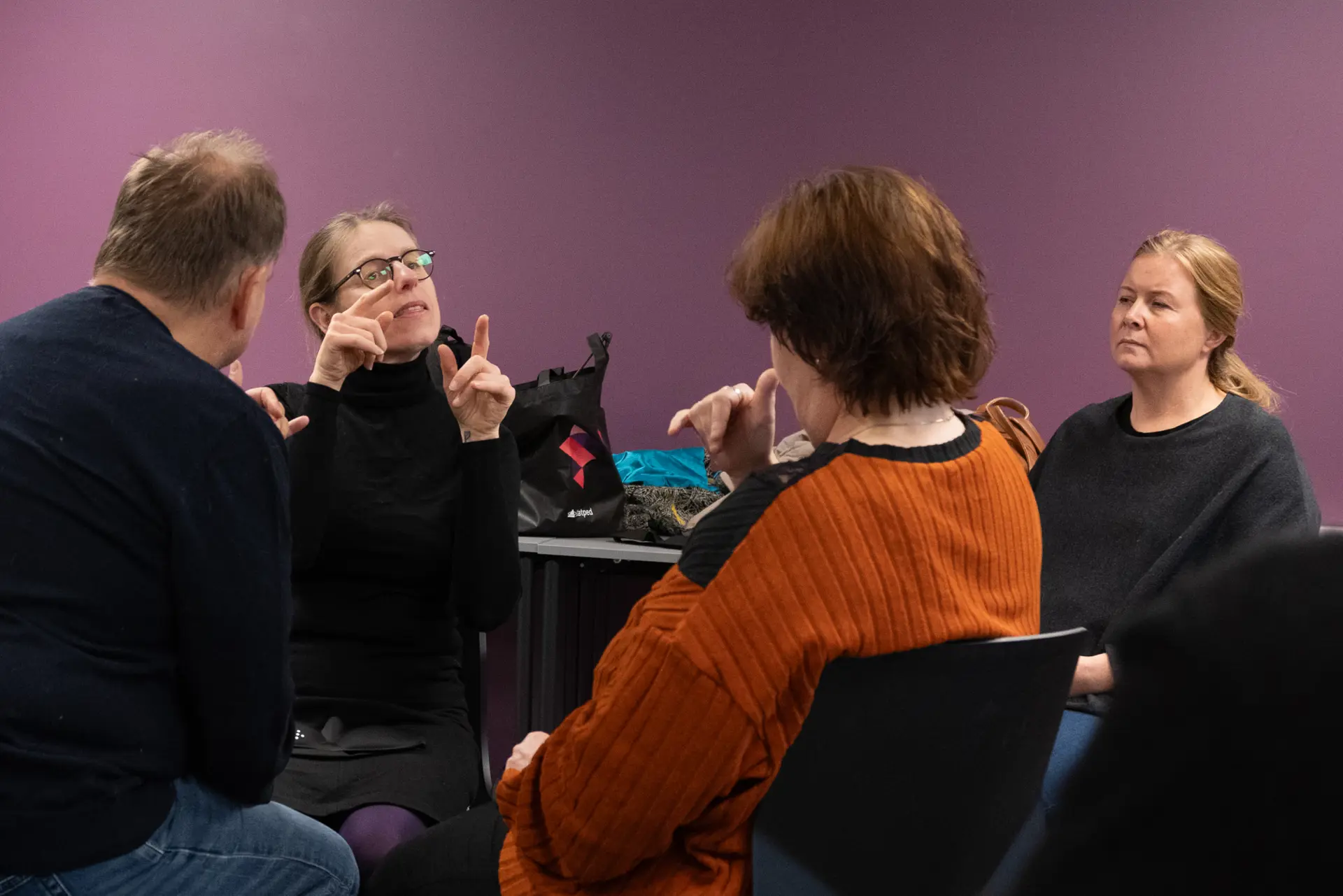 Fire mennesker som sitter rundt hverandre