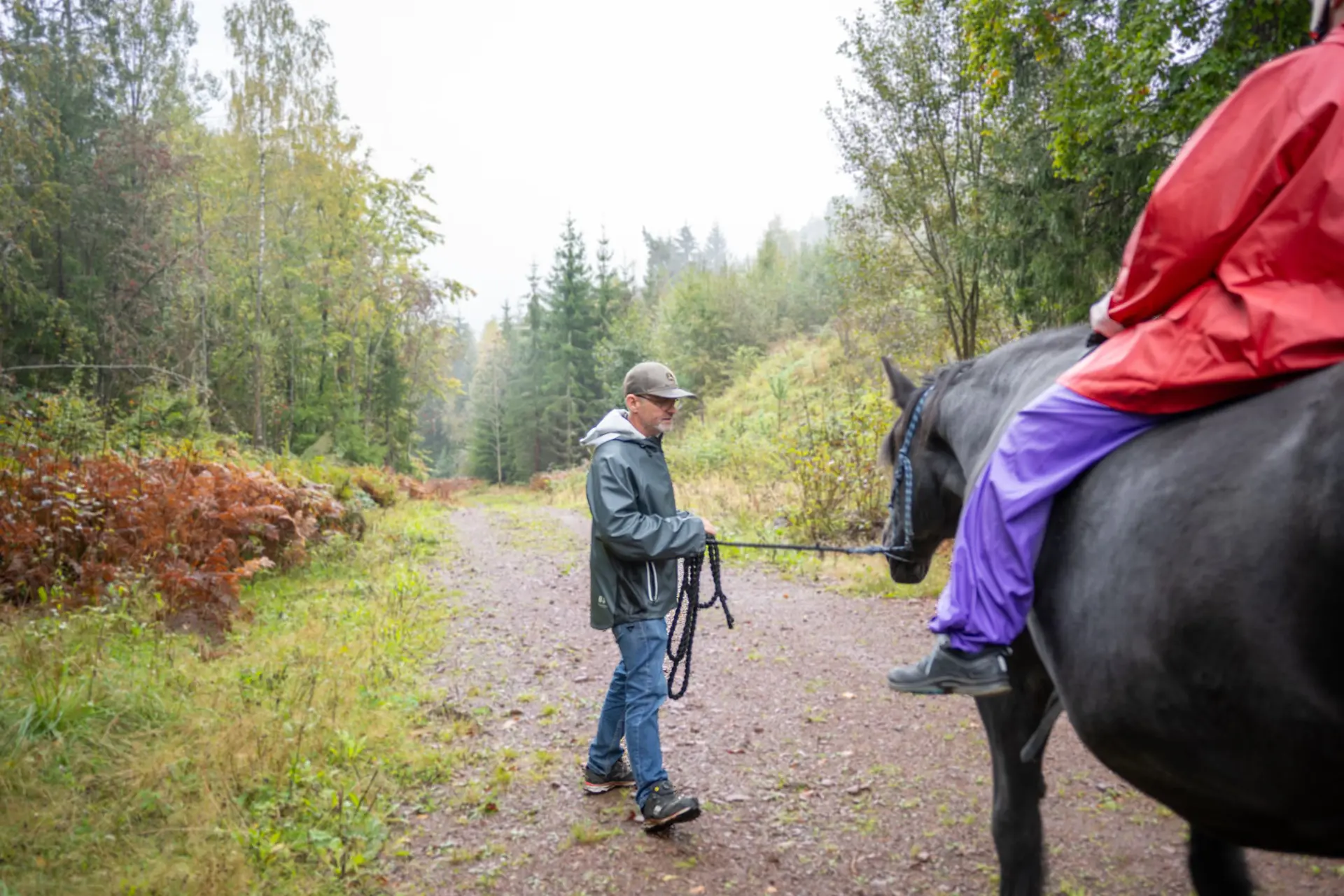 En mann som går med hest på en sti