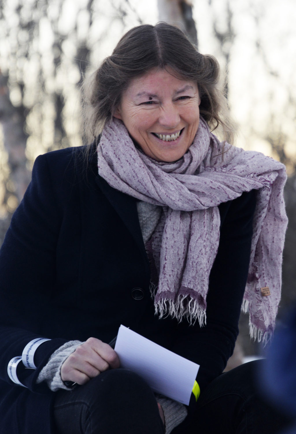 En kvinne som smiler og holder en bok