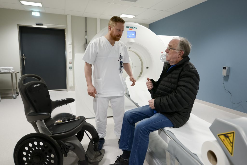 En person som står ved siden av en person i rullestol