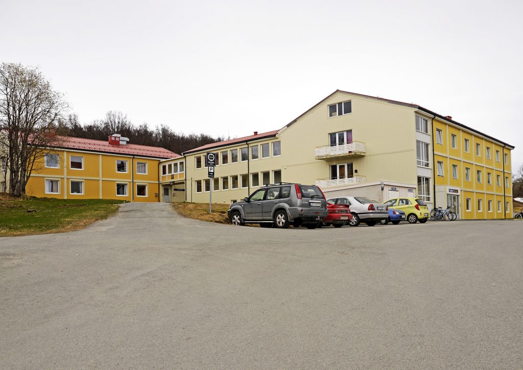 En parkeringsplass med biler og en bygning i bakgrunnen