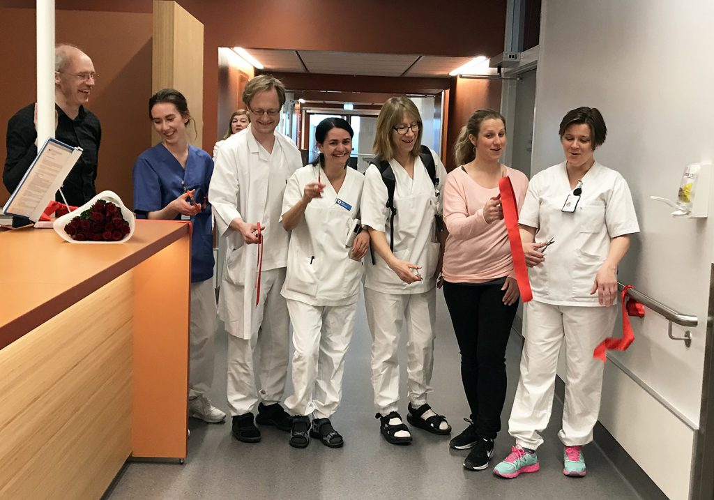 En gruppe mennesker i hvite laboratoriefrakker står i et rom