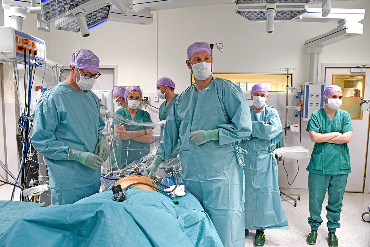 En gruppe mennesker i kirurgiske uniformer og masker i et rom