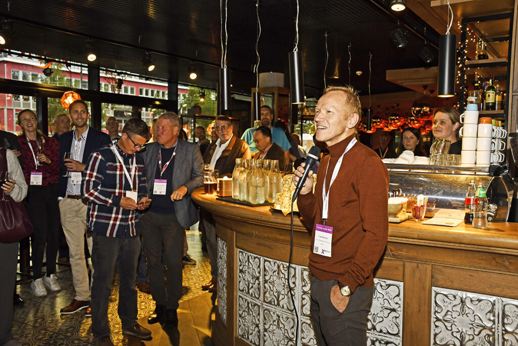 Mann med mikrofon foran bardisk med tilhørere