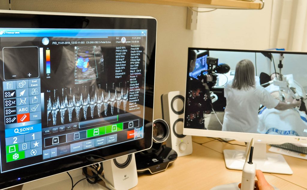 En person i hvit frakk foran en dataskjerm