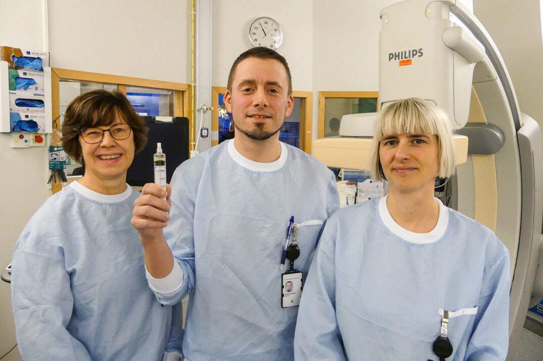 To kvinner og en mann, han står i midten og holder ei sprøyte