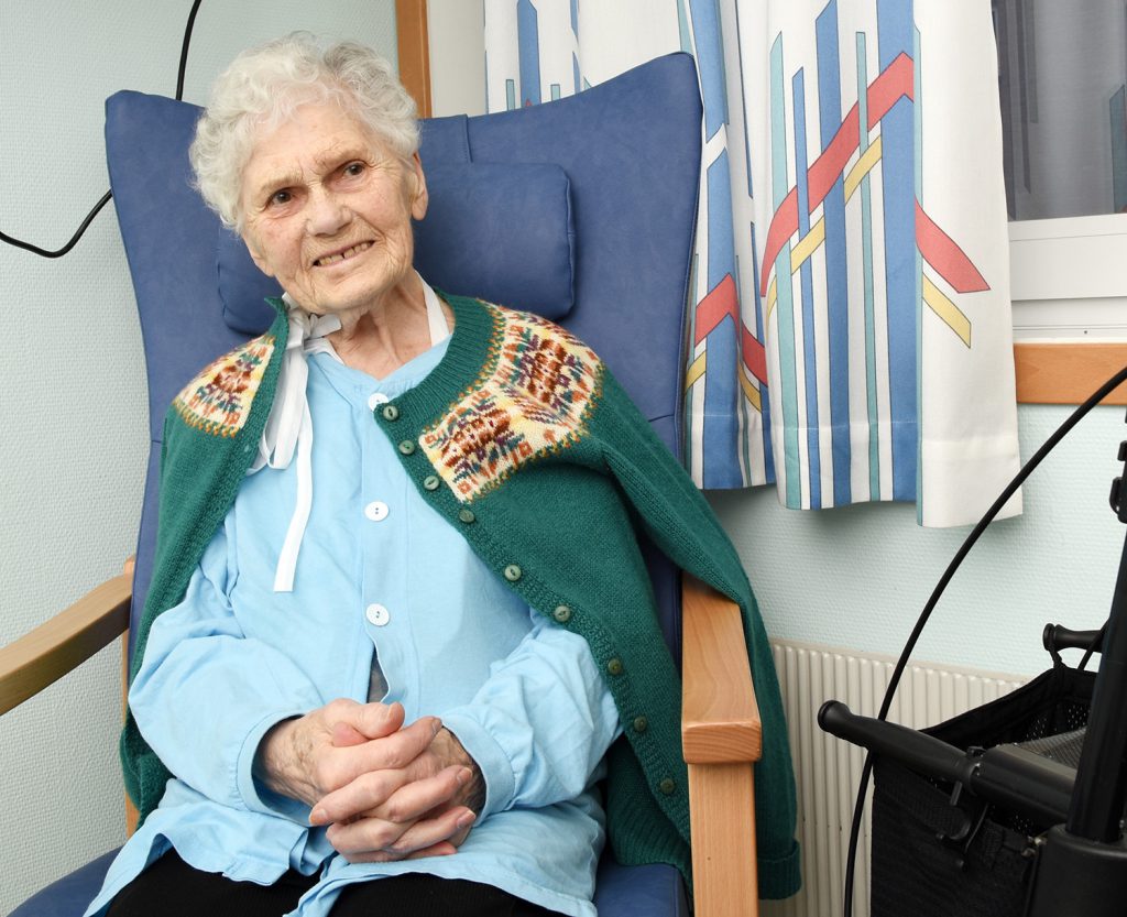 En gammel kvinne som sitter i en stol