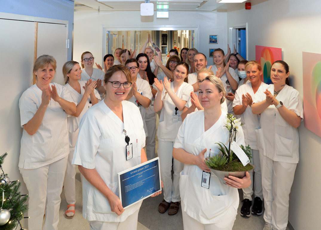 En gruppe mennesker iført hvite laboratoriefrakker som holder planter