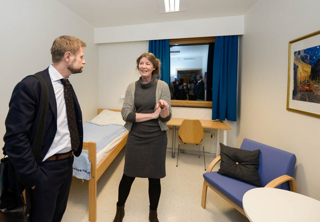 En mann og en kvinne i et rom med seng og stoler