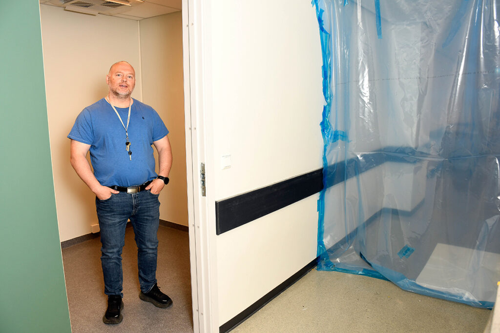 Mann stående i døråpning i korridor