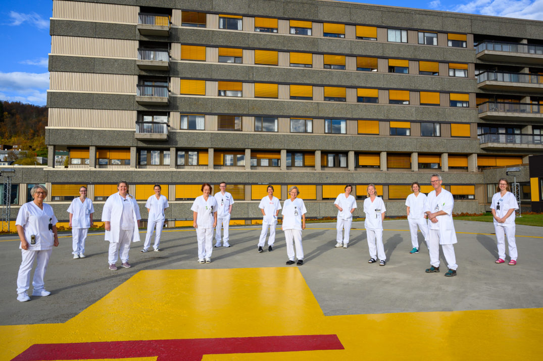 En gruppe mennesker i hvite uniformer som står på en scene foran en bygning