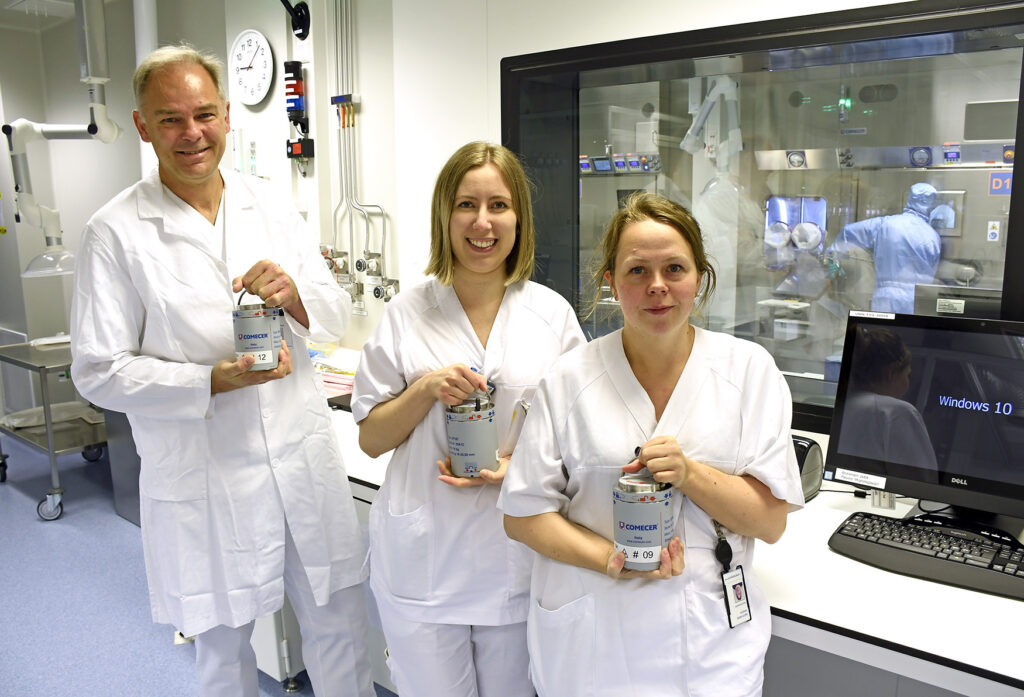 En gruppe mennesker i hvite laboratoriefrakker som holder en flaske væske