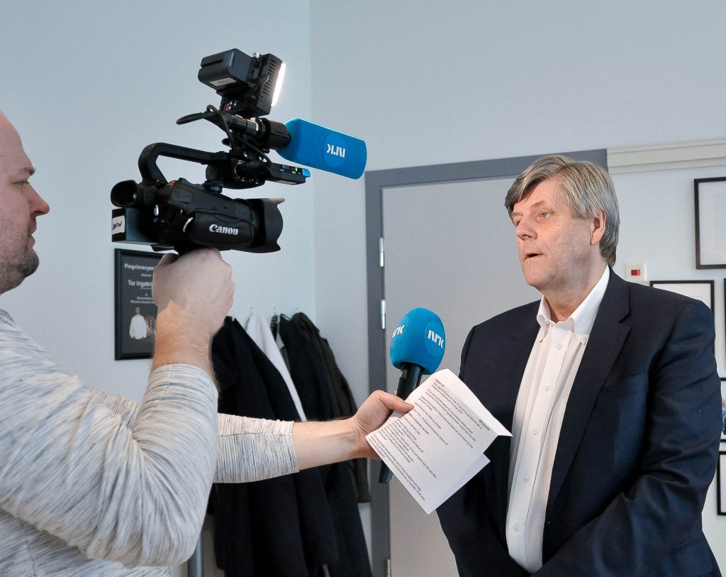 En mann som holder et papir og et kamera på stativ