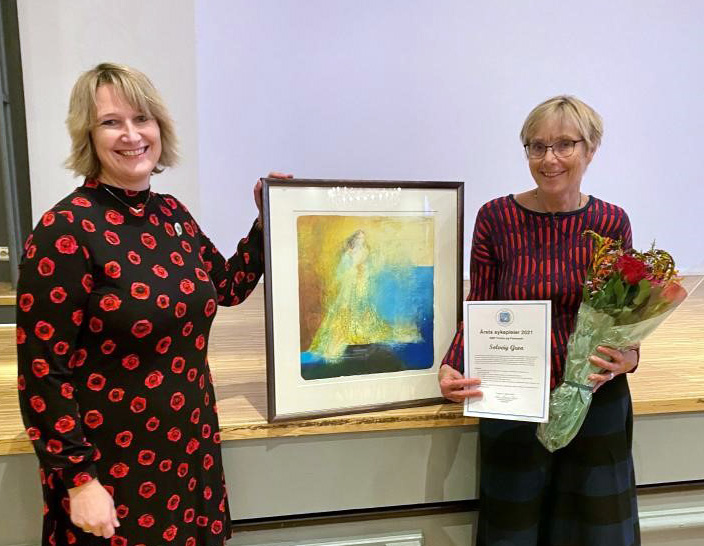 Noen kvinner som holder blomster og et innrammet bilde