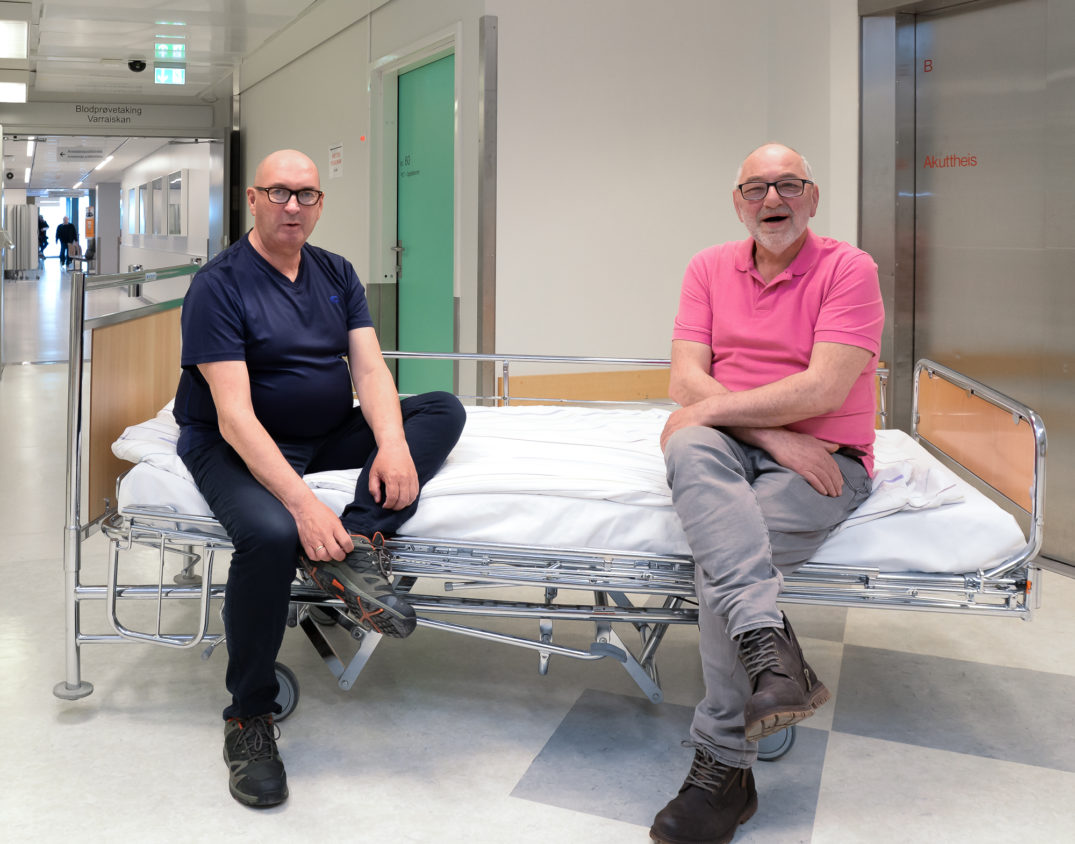 Et par menn som sitter på en sykehusseng