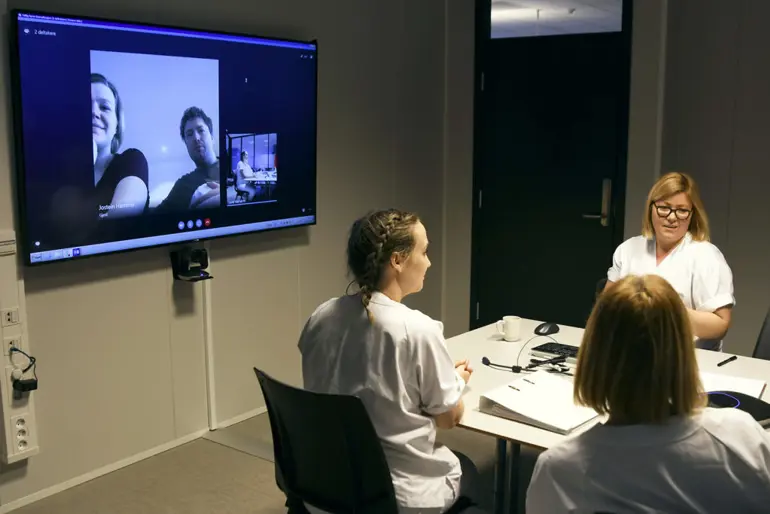 En person som sitter ved et bord og ser på TV