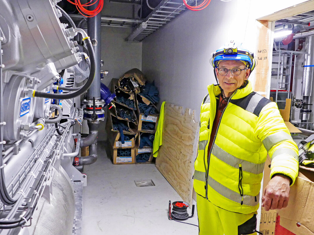 Mann foran varmepumpe som henter opp bergvarme fra fjellet.