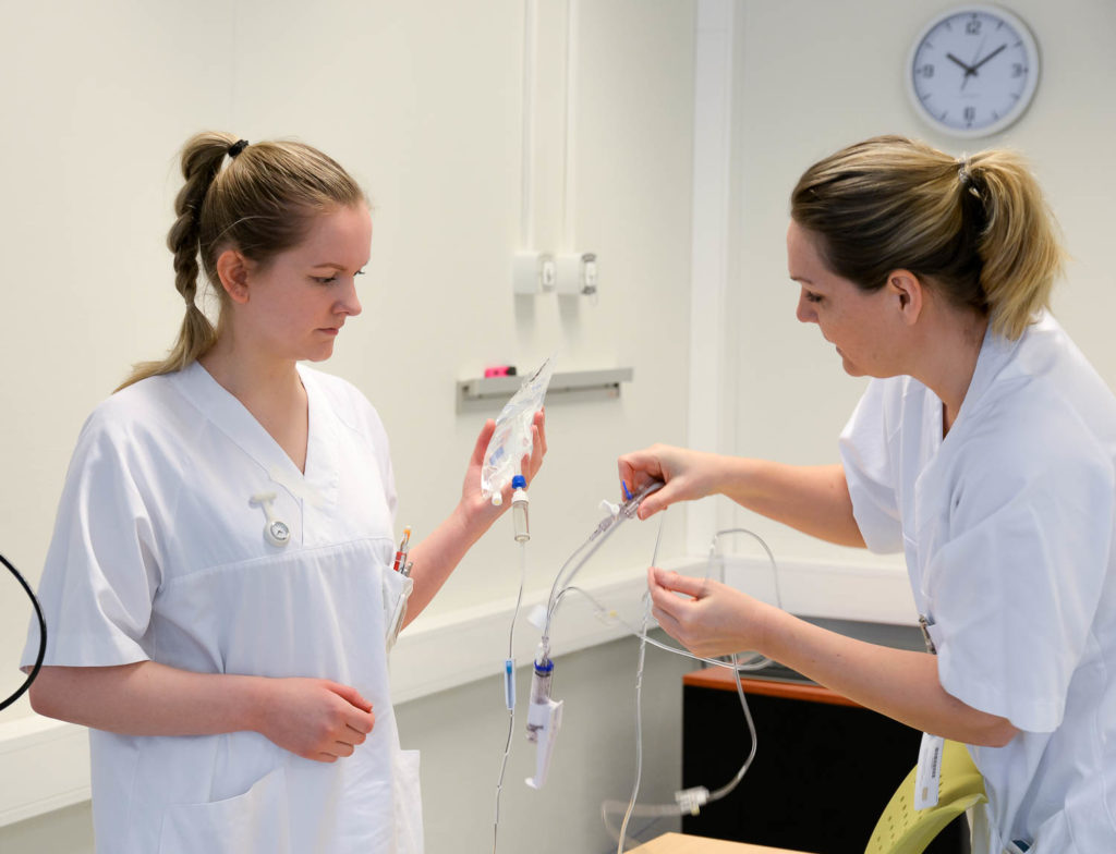 En lege som viser en pasient noe på datamaskinen