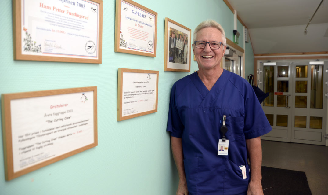 En mann som står foran en vegg med bilder på