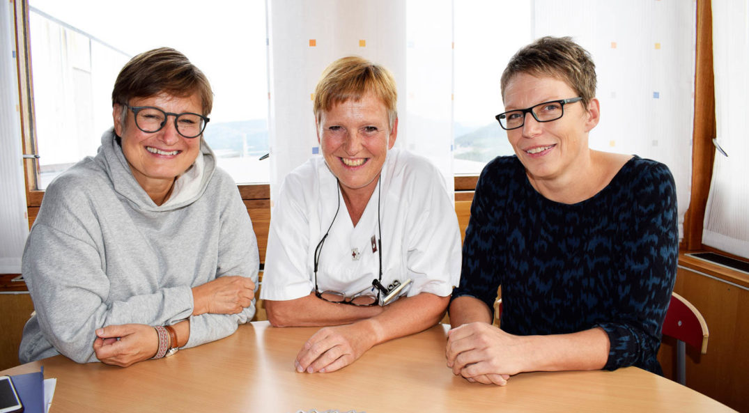 En gruppe mennesker som sitter ved et bord og smiler til kameraet