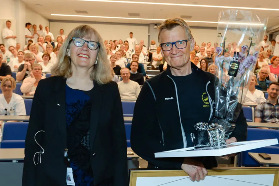 En mann og en kvinne står ved en talerstol med en folkemengde bak seg