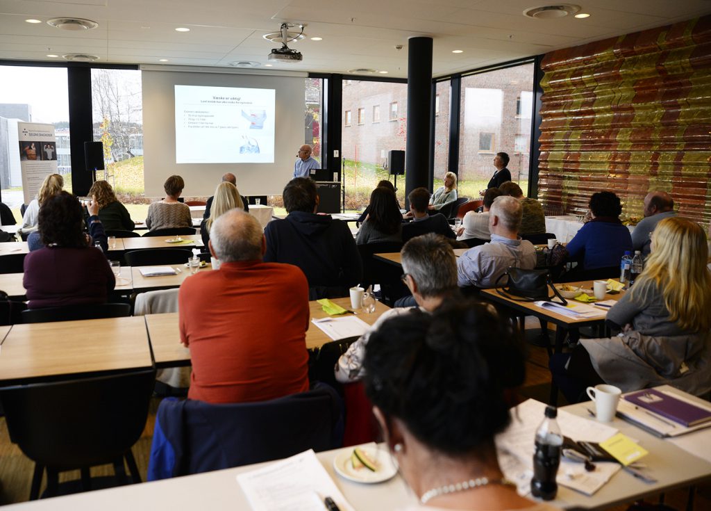 En gruppe mennesker som sitter i et rom og ser på en skjerm