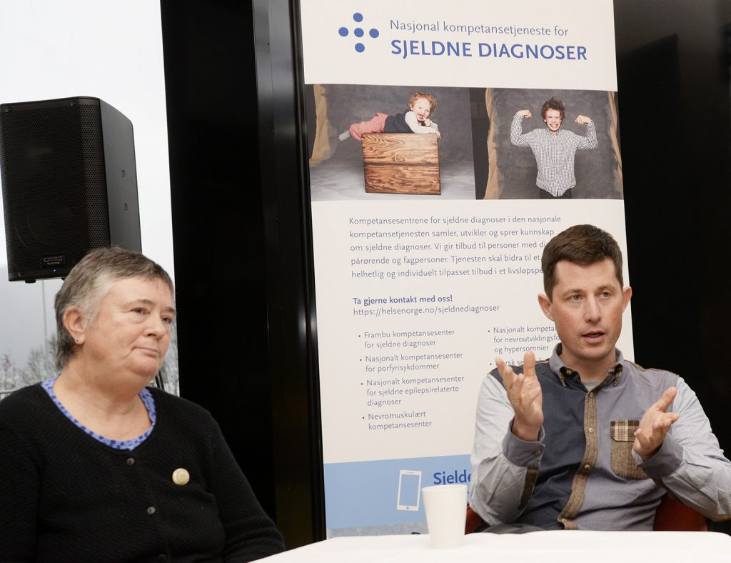 En mann og en kvinne sitter ved et bord med en plakat