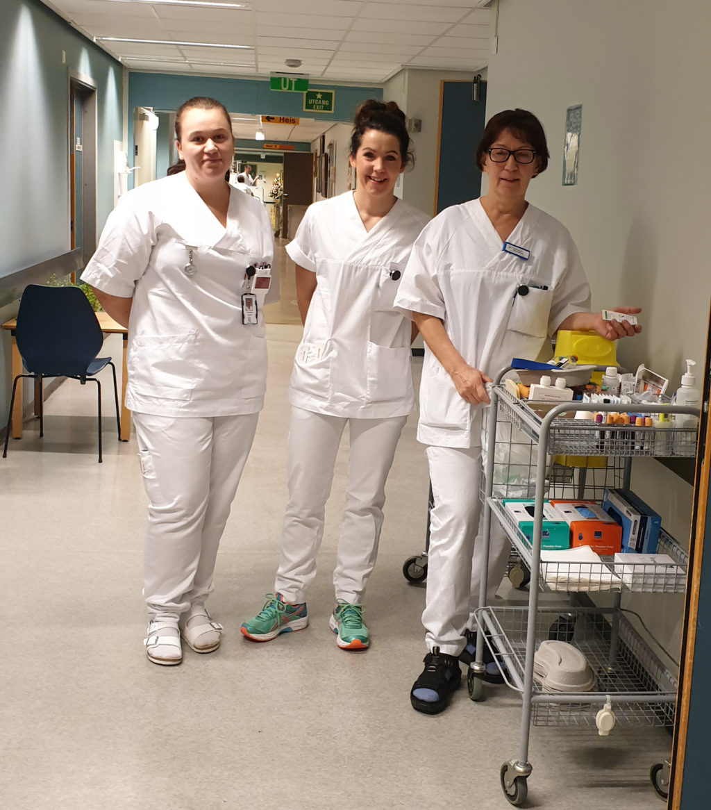 En gruppe mennesker i hvite laboratoriefrakker står i et rom