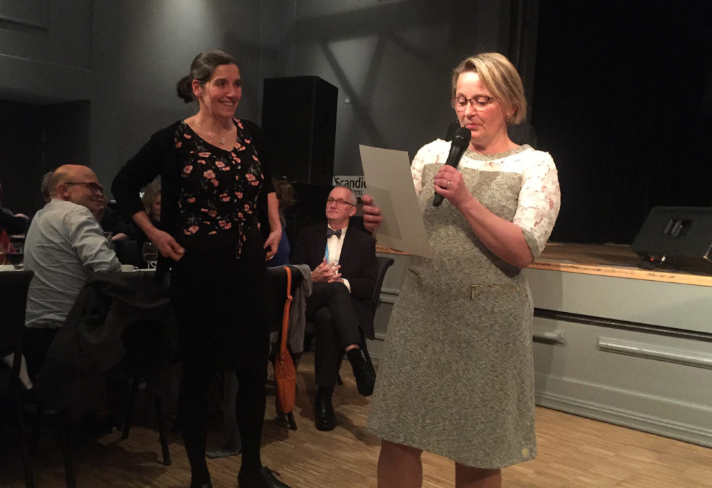 En person som holder en mikrofon og en person som holder et papir