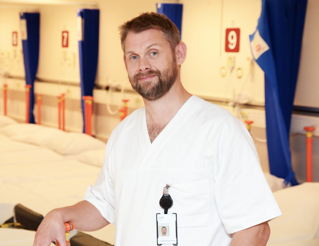 En mann som sitter i en sykehusseng