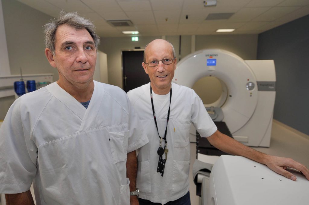 Et par menn i hvite laboratoriefrakker som står foran en maskin