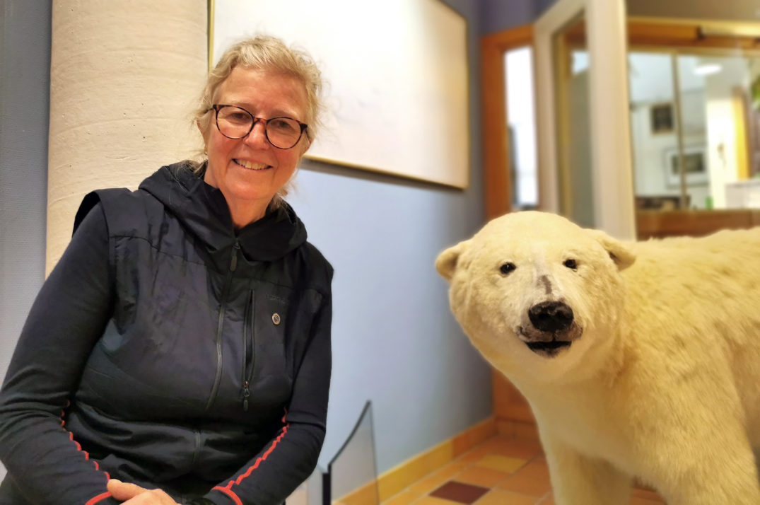 En person som smiler ved siden av en isbjørn