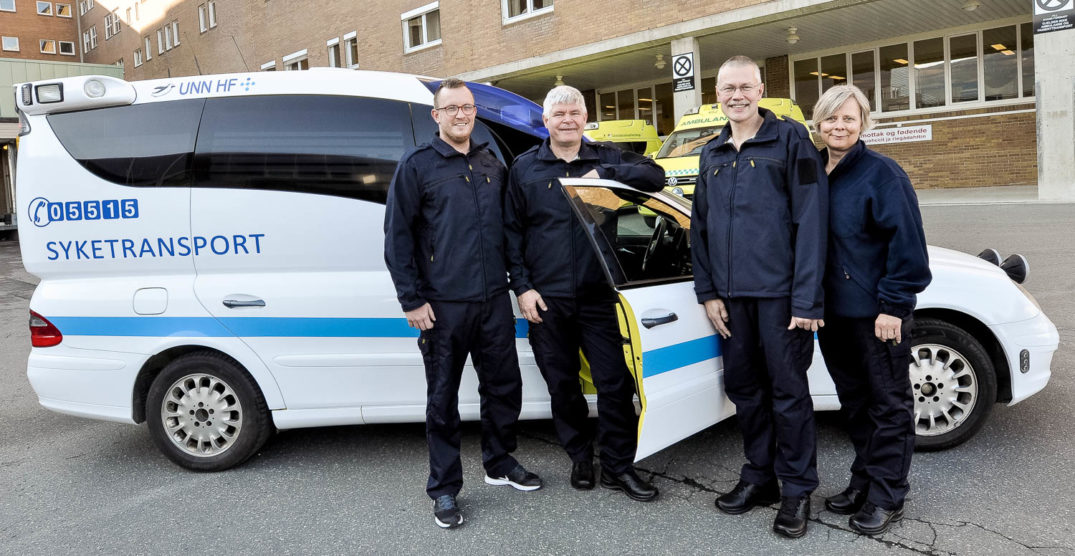 En gruppe mennesker som står ved siden av en politibil