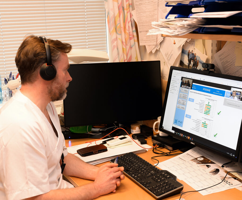 En mann med hodetelefoner som sitter ved et skrivebord med en datamaskin