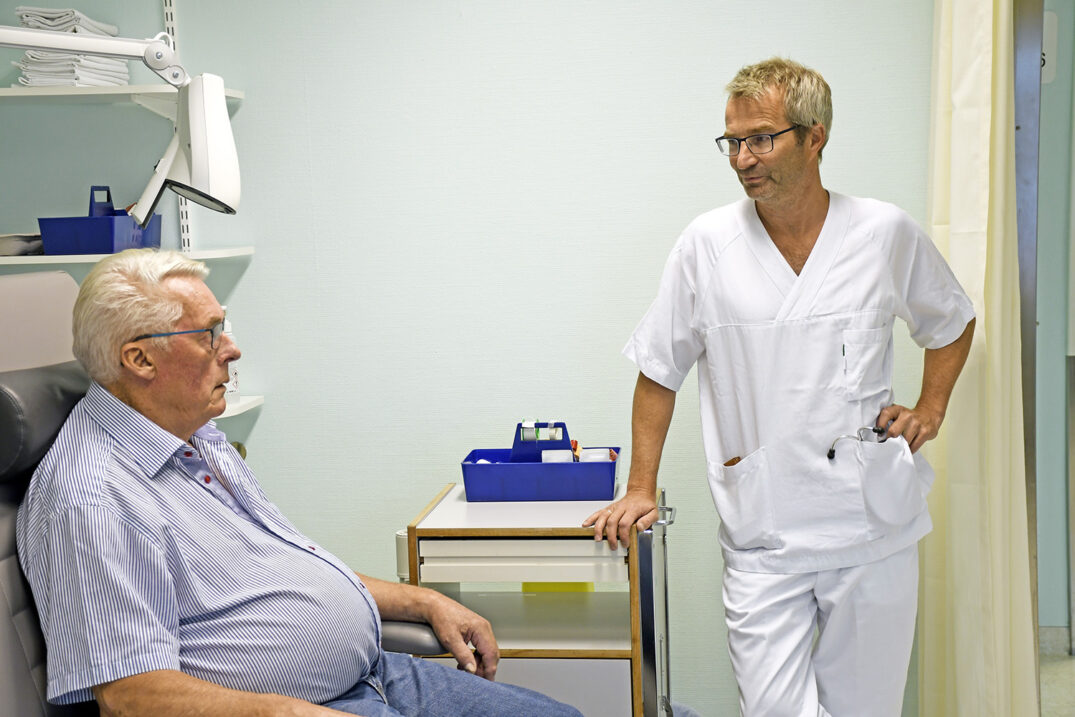 En lege som snakker med en gammel mann