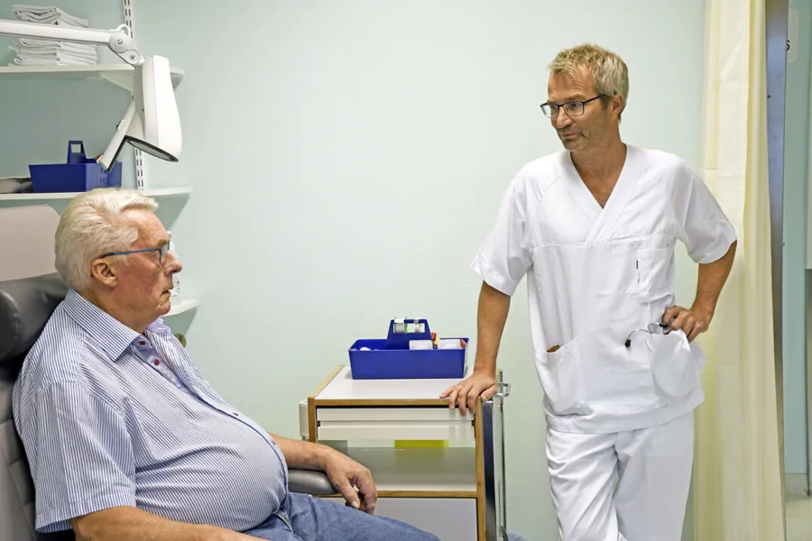 En lege som snakker med en gammel mann