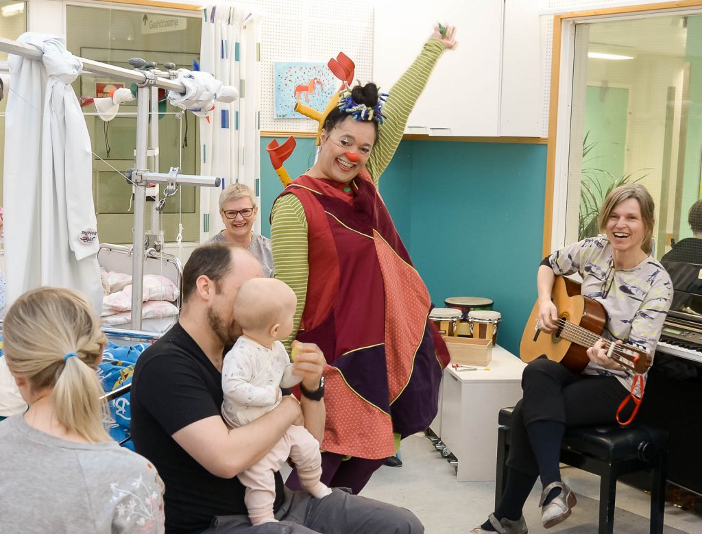 En mann i plagg som holder en baby og en kvinne som holder en baby