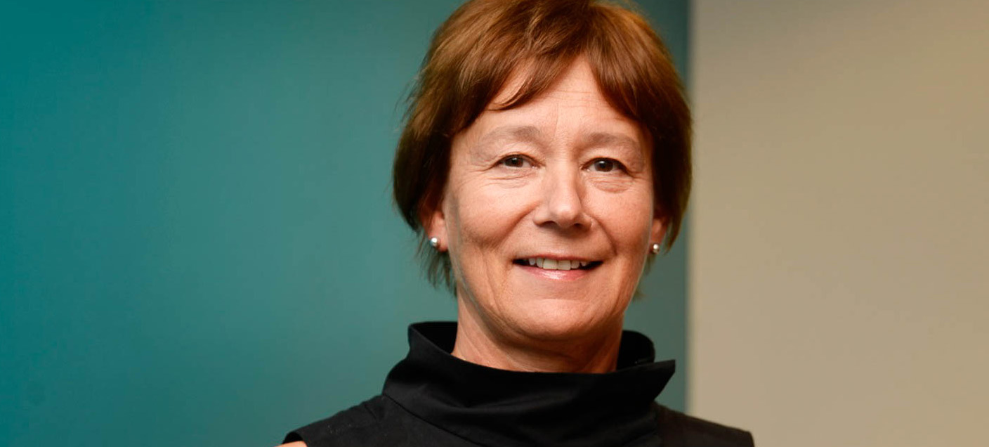 En person som smiler foran en blå vegg