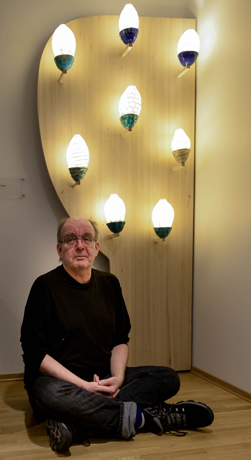 En mann som sitter på gulvet med en gruppe lys over seg