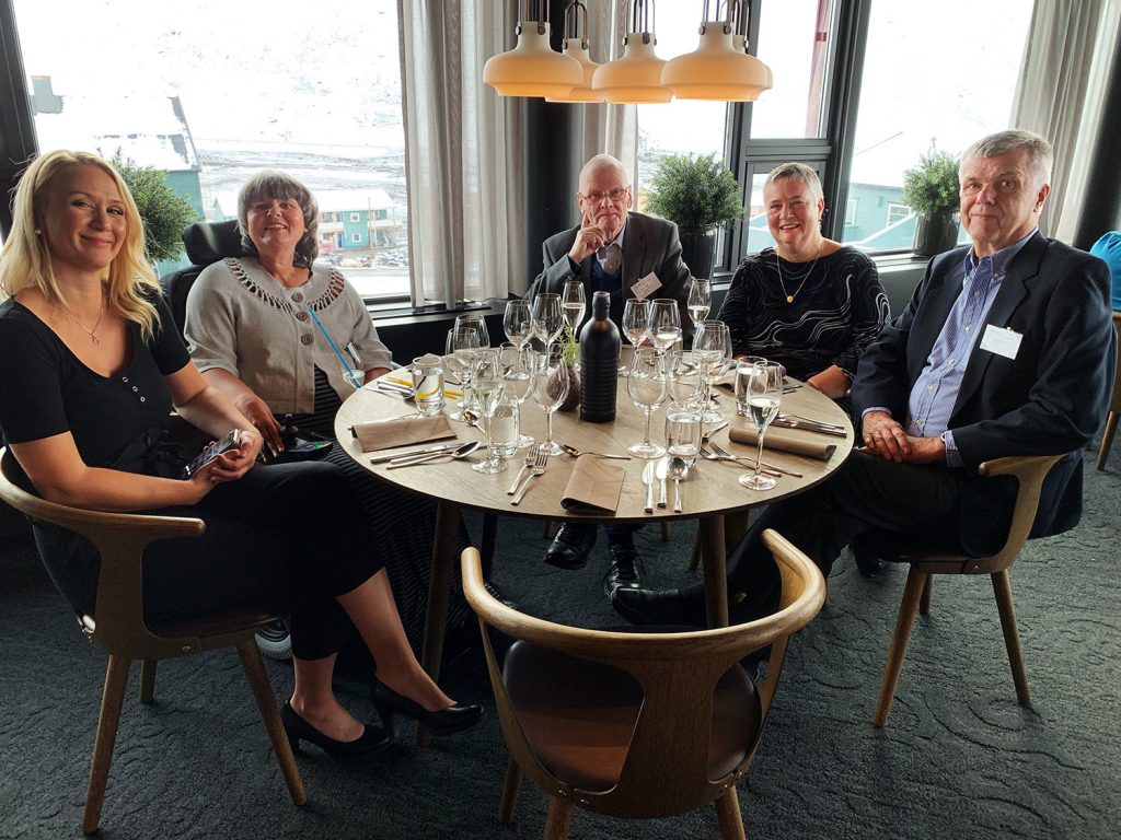 En gruppe mennesker som sitter rundt et bord med vinglass