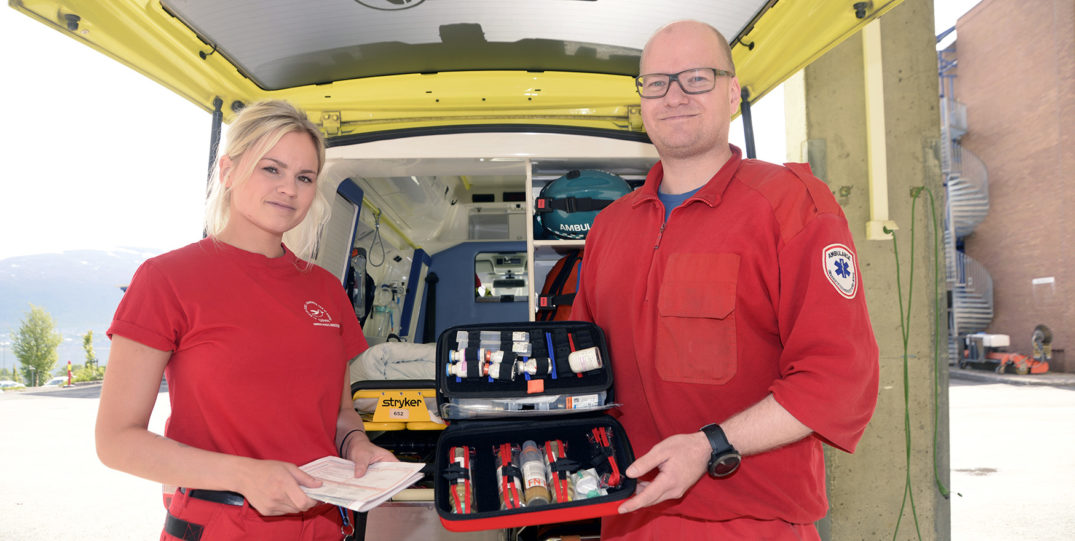 En mann og en kvinne står foran en bil med en kjøleboks