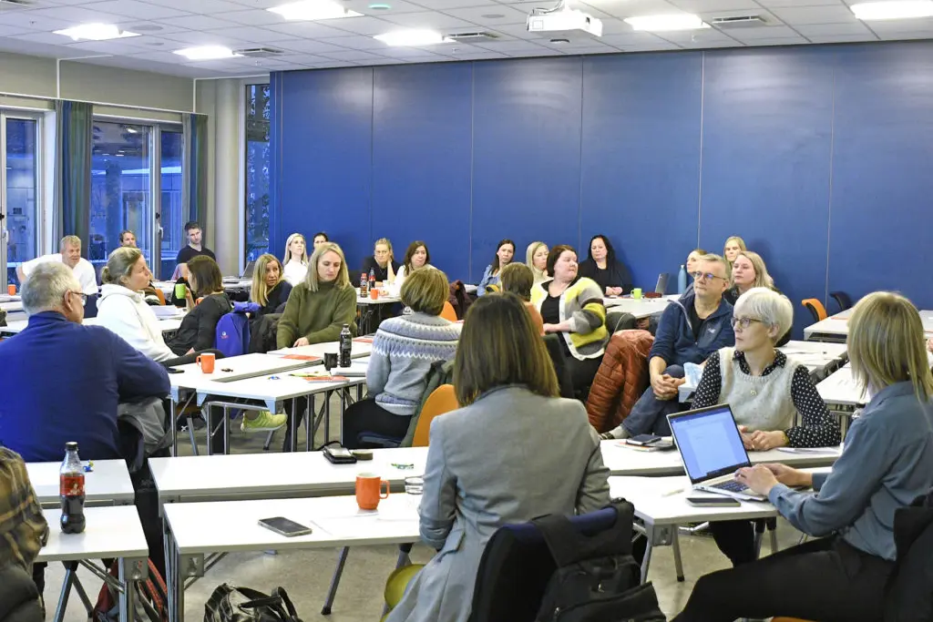 En gruppe mennesker som sitter ved bord med bærbare PC-er