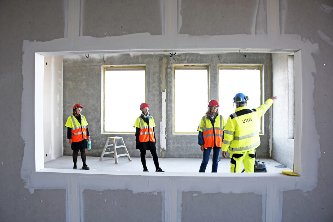 En gruppe menn i sikkerhetsvester står i et rom