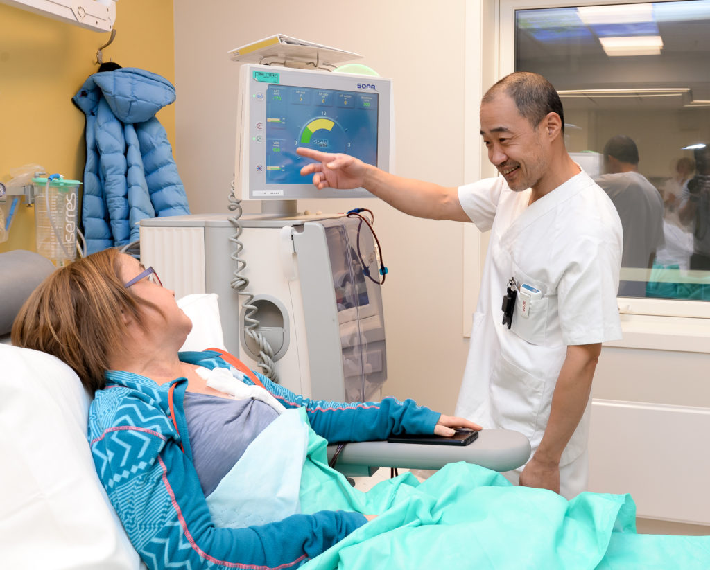 En lege som viser pasienten noe på nettbrettet