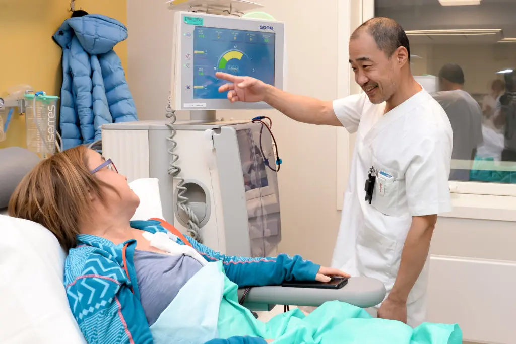 En lege som viser pasienten noe på nettbrettet