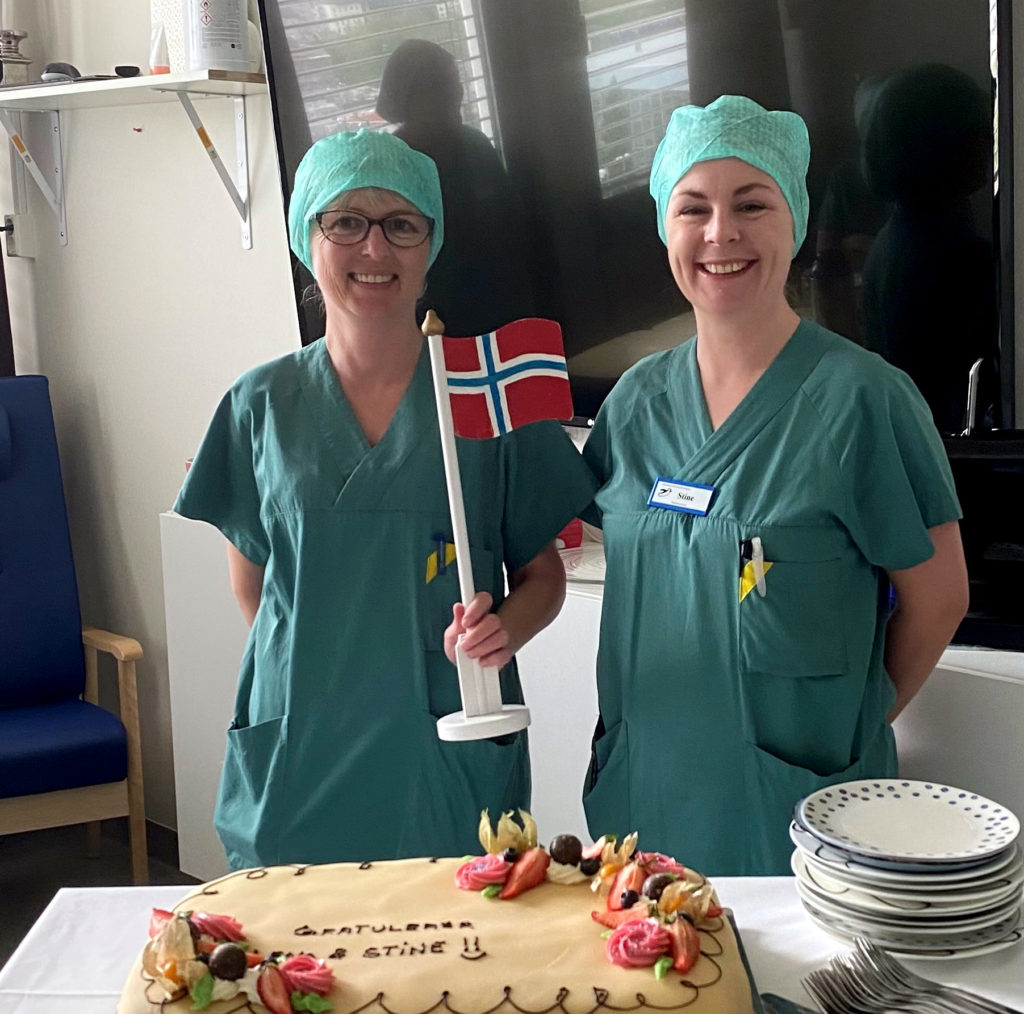 Kvinner i kirurgiske klær som skjærer kake