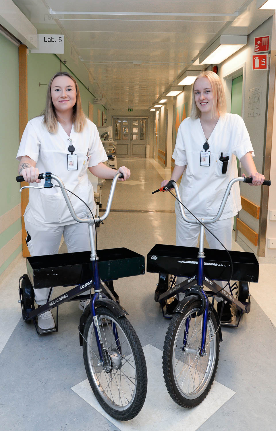 Et par kvinner i hvite skjorter som står ved siden av en sykkel