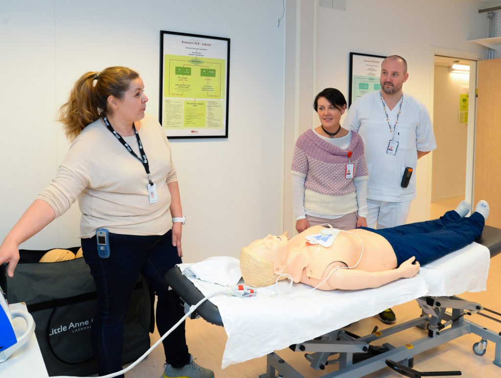 En gruppe mennesker som står rundt en person som ligger på en sykehusseng